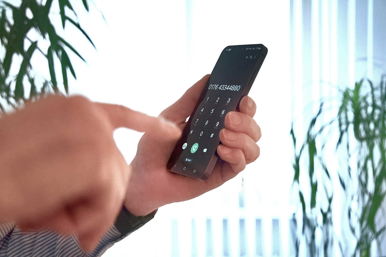 Ein Finger tippt eine Telefonnummer in ein Smartphone.