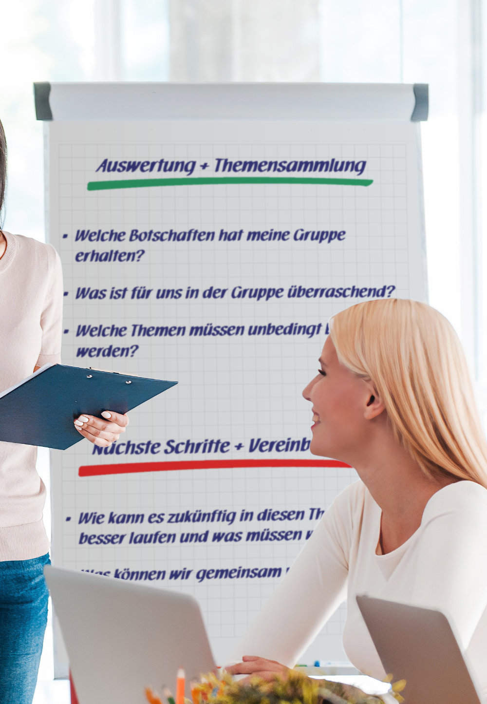 Eine Workshop-Teilnehmerin sitzt am Tisch und blickt auf eine Moderatorin sowie ein danebenstehendes Flipchart.